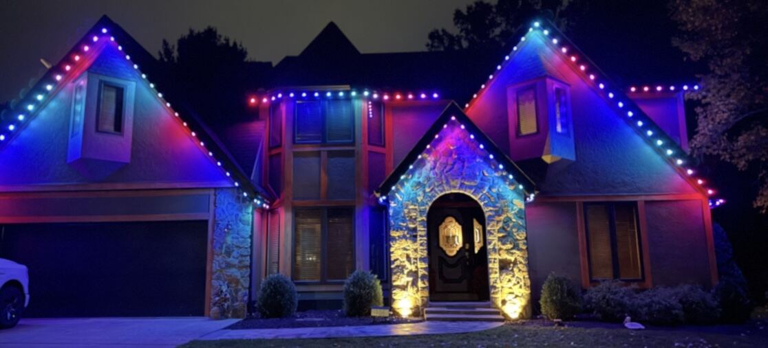 Permanent color-changing roofline lighting on a stucco and stone home