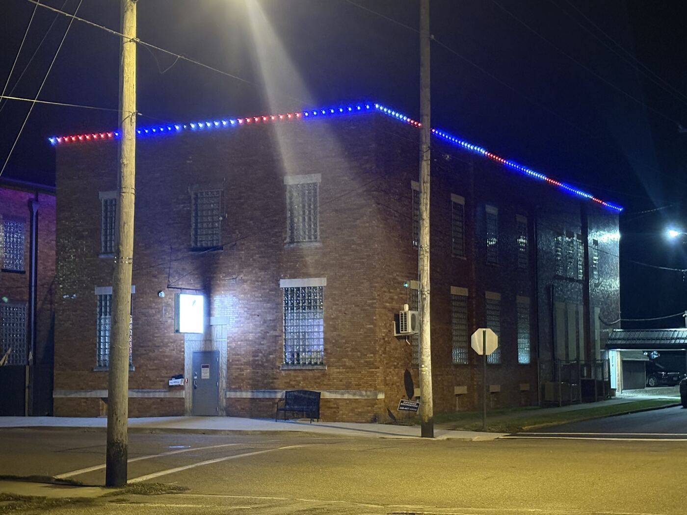Permanent red, white, and blue trim lighting on a commercial brick building roofline