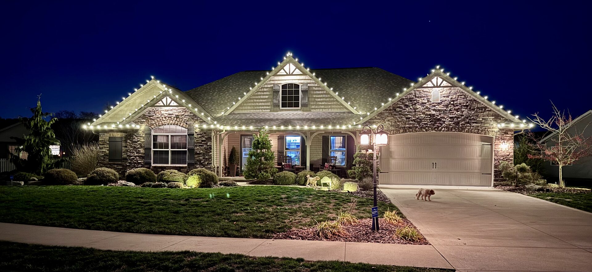 Landscape lighting glowing along a home's foundation bed at dusk